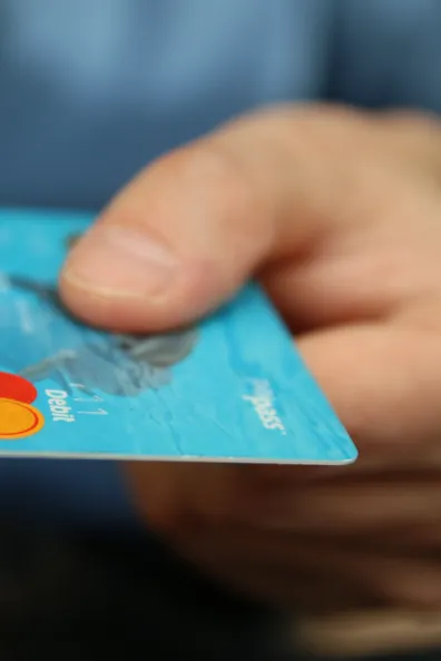 La main d'un homme tendant une carte de crédit bleue